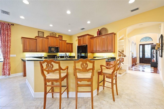 kitchen with black appliances, a kitchen breakfast bar, and light tile patterned floors