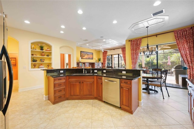 kitchen with sink, built in features, a center island with sink, ceiling fan with notable chandelier, and appliances with stainless steel finishes