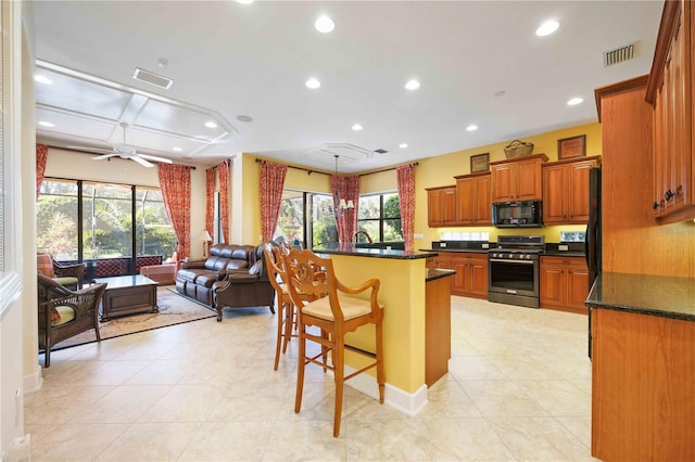 kitchen featuring ceiling fan, a center island, stainless steel range oven, a breakfast bar, and light tile patterned flooring