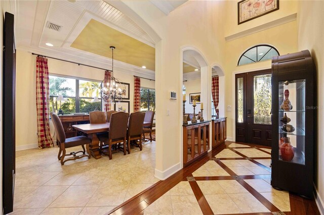 foyer featuring crown molding, light tile patterned floors, and a notable chandelier