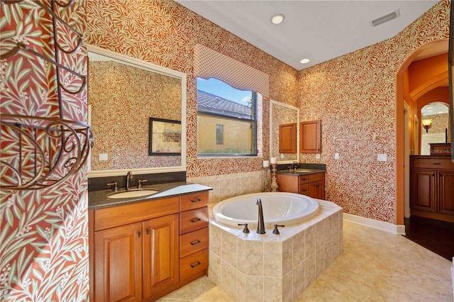 bathroom featuring tile patterned floors, vanity, and a relaxing tiled tub