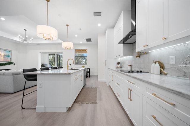 kitchen featuring white cabinets, sink, hanging light fixtures, light wood-type flooring, and black electric cooktop