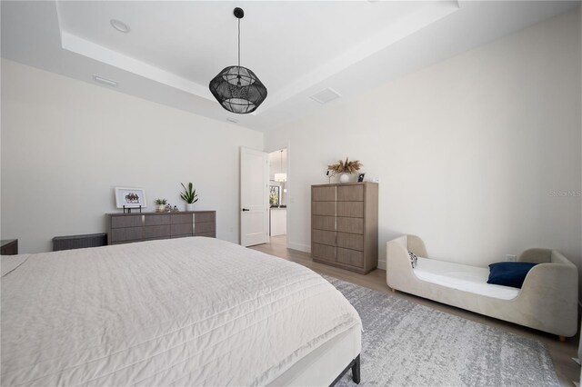 bedroom with a tray ceiling and light hardwood / wood-style flooring