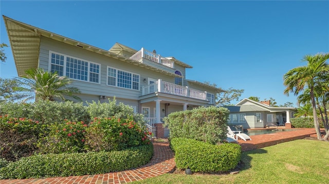 rear view of property featuring a yard and a balcony