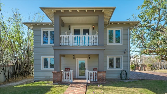 rear view of property featuring a porch, a balcony, and a lawn