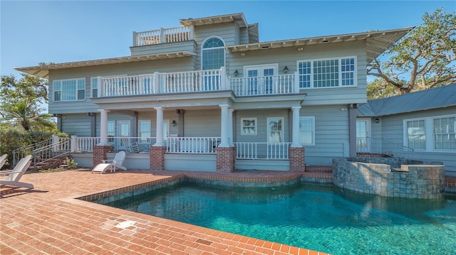 back of property featuring a balcony and a fenced in pool