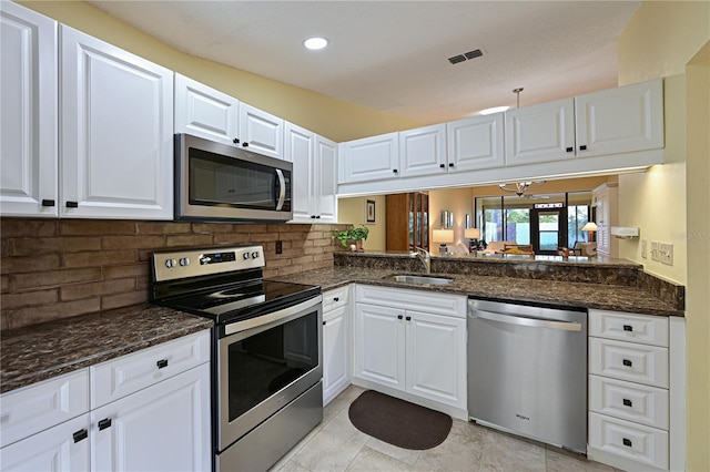 kitchen featuring dark stone countertops, sink, white cabinetry, and stainless steel appliances