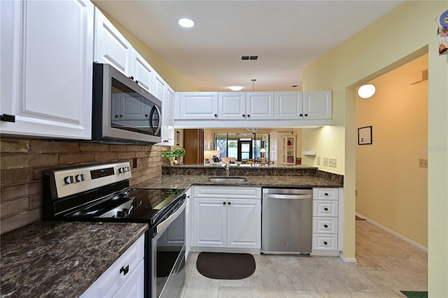 kitchen featuring sink, backsplash, dark stone countertops, white cabinets, and appliances with stainless steel finishes