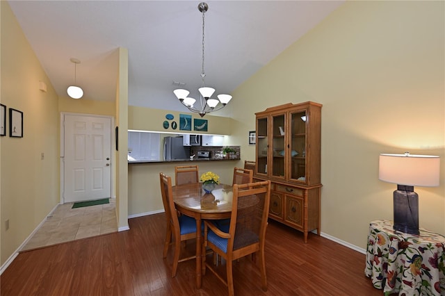 dining room with wood-type flooring, vaulted ceiling, and an inviting chandelier