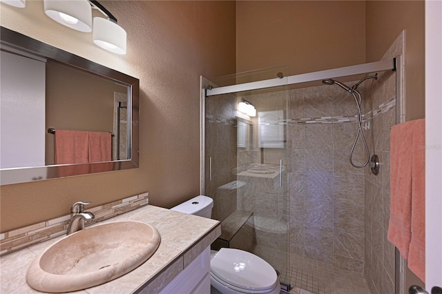 bathroom featuring vanity, a shower with shower door, and toilet