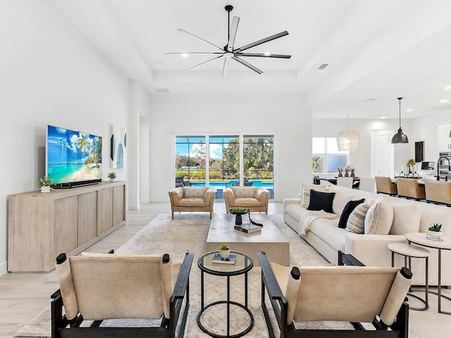 living room featuring light wood-type flooring, a tray ceiling, and a chandelier