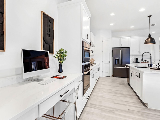 kitchen featuring pendant lighting, white cabinets, tasteful backsplash, light hardwood / wood-style floors, and stainless steel appliances