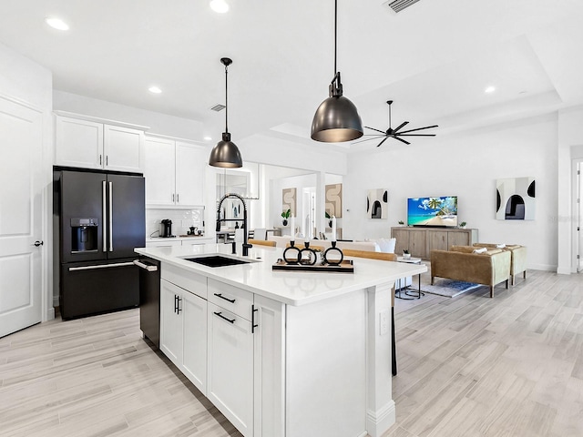 kitchen featuring white cabinetry, high end refrigerator, a center island with sink, and sink