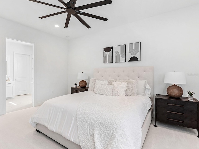 bedroom with ceiling fan, light carpet, and ensuite bath