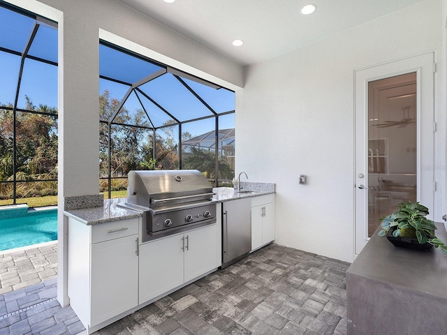 view of patio / terrace with an outdoor kitchen, a grill, a lanai, and sink