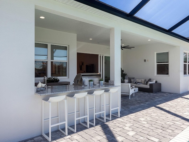 view of patio / terrace with an outdoor hangout area, an outdoor bar, ceiling fan, and exterior kitchen