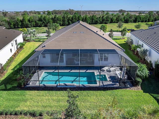 rear view of house featuring a yard and glass enclosure