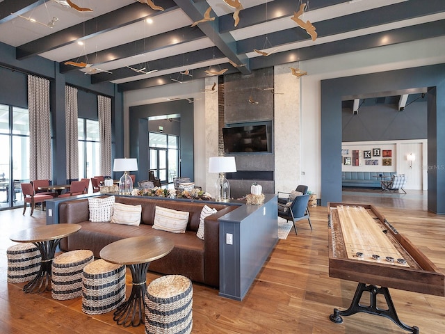 interior space featuring beam ceiling, light wood-type flooring, and a high ceiling