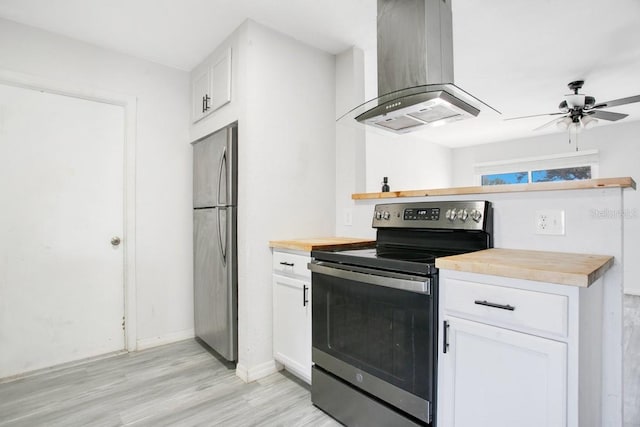 kitchen with stainless steel appliances, island range hood, white cabinets, and butcher block countertops