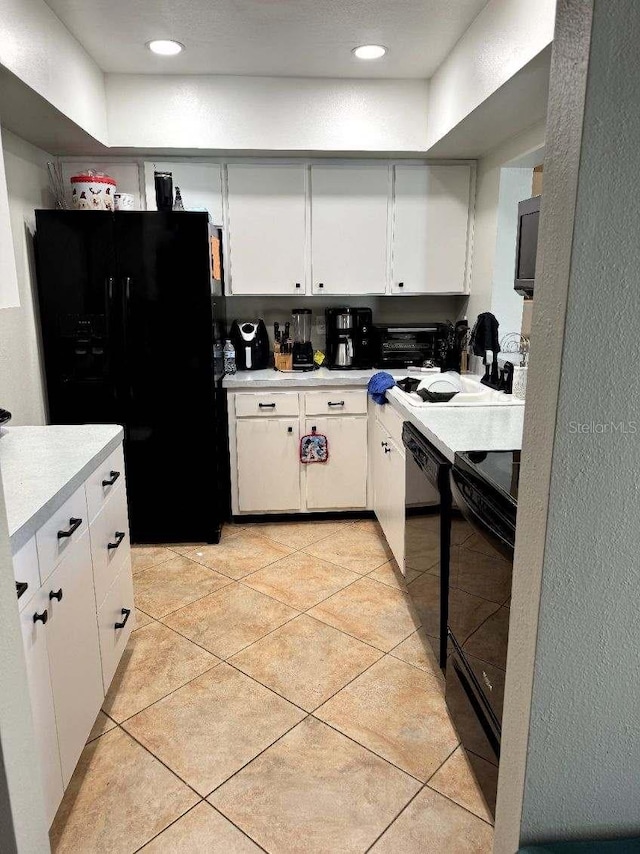 kitchen with sink, white cabinets, black appliances, and light tile patterned floors