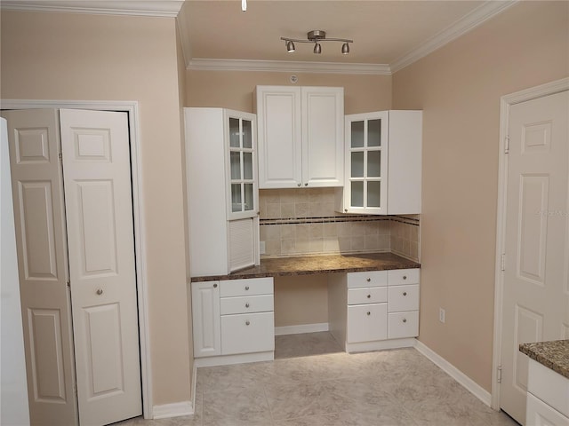 kitchen featuring backsplash, crown molding, white cabinets, and built in desk