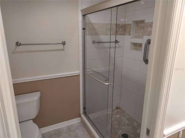 bathroom featuring tile patterned flooring, toilet, and a shower with door