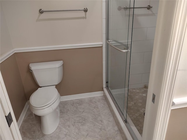 bathroom featuring tile patterned flooring, toilet, and walk in shower