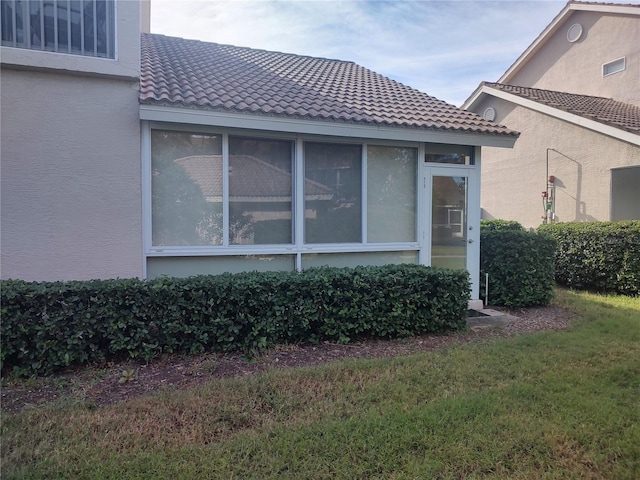 view of side of property featuring a sunroom and a lawn