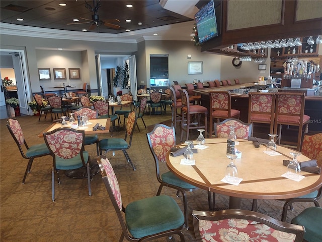 dining room featuring ceiling fan, ornamental molding, and indoor bar