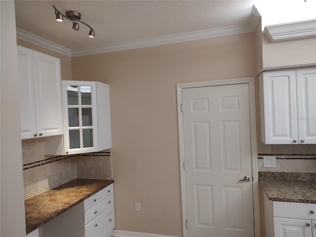 kitchen with track lighting, white cabinets, ornamental molding, a textured ceiling, and tasteful backsplash