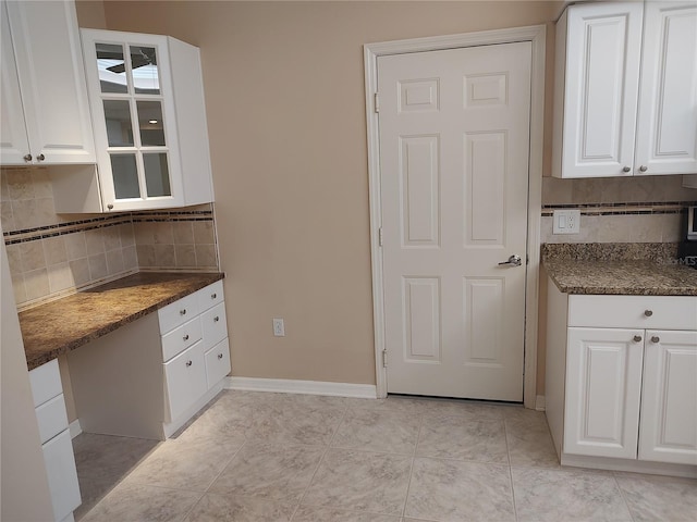 kitchen featuring white cabinets, built in desk, tasteful backsplash, and light tile patterned flooring