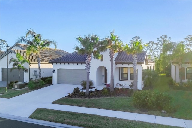 mediterranean / spanish-style house featuring a garage and a front lawn