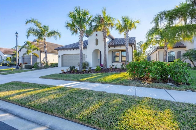 mediterranean / spanish home featuring a front yard and a garage