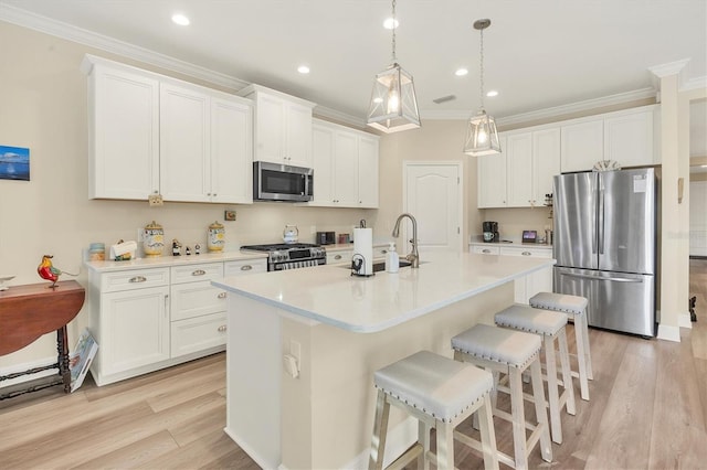 kitchen featuring white cabinets, stainless steel appliances, light hardwood / wood-style flooring, and an island with sink