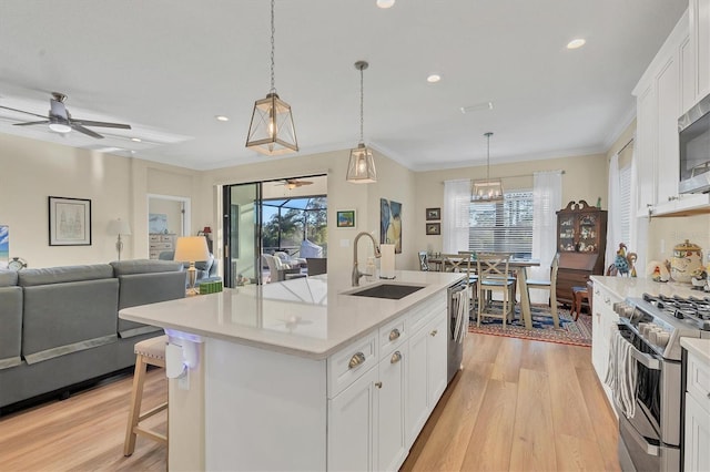 kitchen featuring a center island with sink, white cabinets, sink, and a wealth of natural light