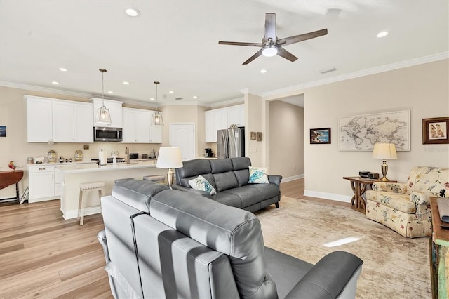 living room with ceiling fan, ornamental molding, and light wood-type flooring