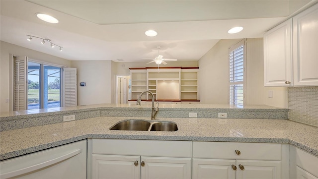 kitchen with white cabinetry, white dishwasher, sink, and light stone counters