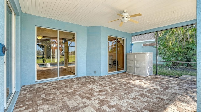 unfurnished sunroom featuring ceiling fan