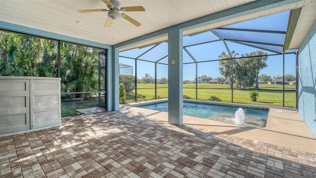 view of swimming pool featuring ceiling fan, a yard, glass enclosure, a patio area, and pool water feature