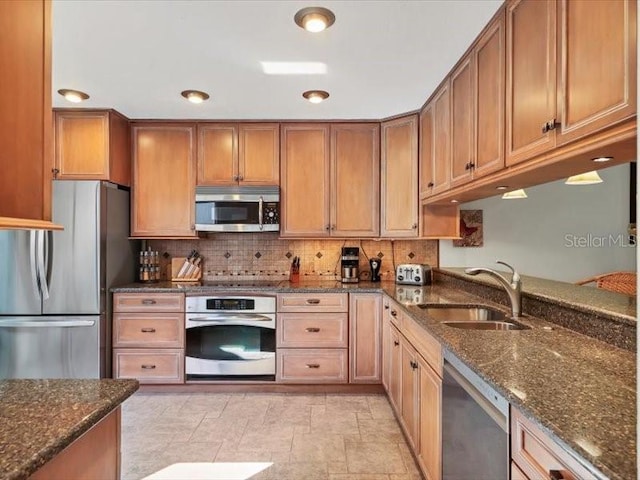 kitchen featuring backsplash, dark stone countertops, sink, and appliances with stainless steel finishes