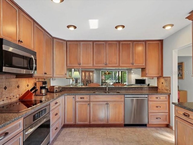 kitchen with backsplash, dark stone countertops, sink, and stainless steel appliances