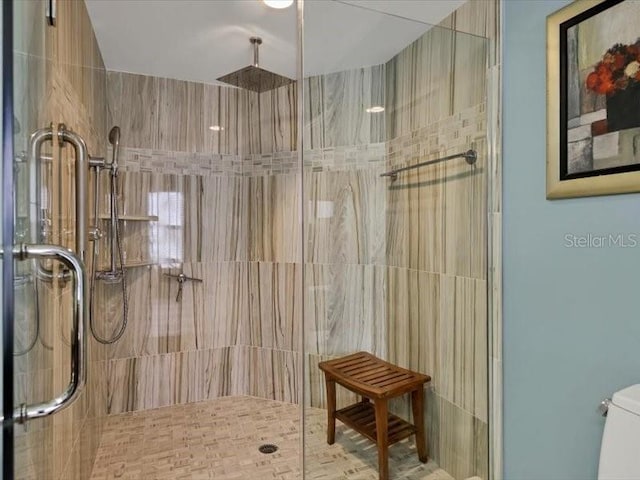 bathroom featuring toilet and a shower with door