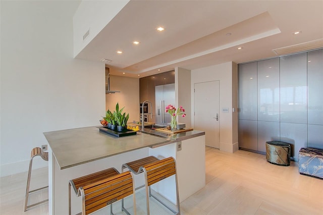 kitchen with a breakfast bar, stainless steel built in fridge, sink, gray cabinets, and kitchen peninsula