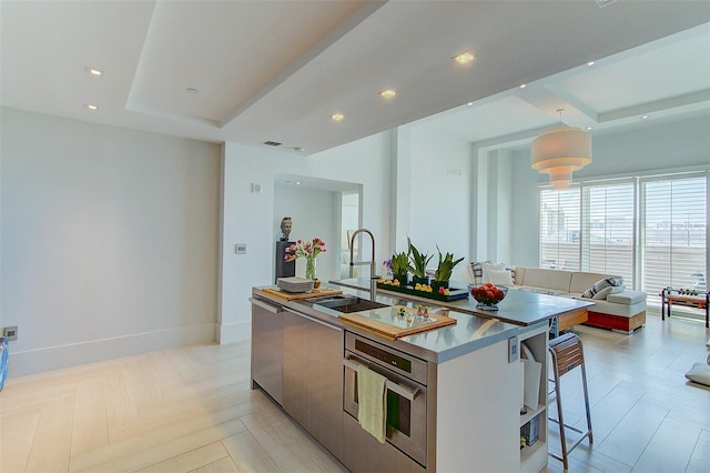 kitchen featuring a kitchen island with sink, sink, stainless steel appliances, a breakfast bar area, and light parquet flooring