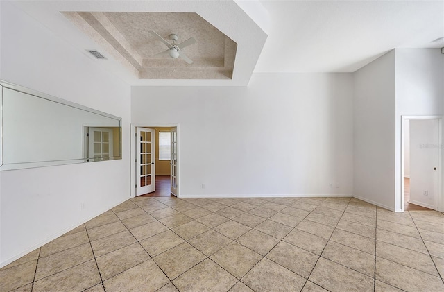 spare room with a raised ceiling, ceiling fan, and light tile patterned flooring