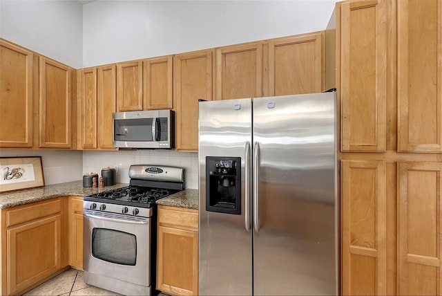 kitchen with backsplash, light tile patterned floors, stone countertops, and appliances with stainless steel finishes