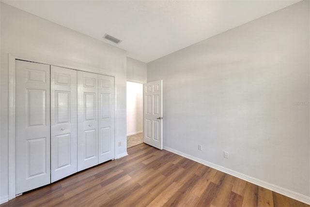 unfurnished bedroom with dark wood-type flooring and a closet