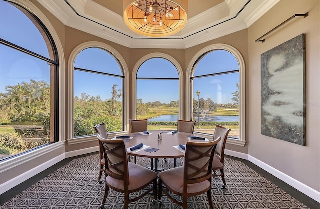 dining space featuring a water view, a raised ceiling, and crown molding