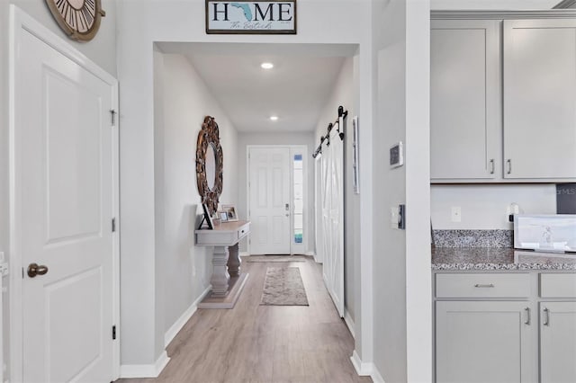 corridor featuring a barn door and light hardwood / wood-style flooring