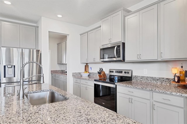 kitchen with light stone counters, sink, and stainless steel appliances